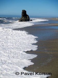 Одиноко торчащая скала на пляже в линии прибоя океана