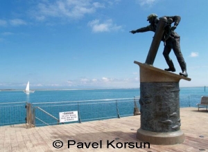 Памятник морякам - моряк указывающий на катамаран в океане