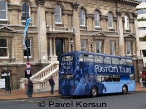 Туристический двухэтажный автобус синего цвета перед зданием мерии в Дьюндине