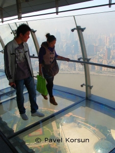 Пара китайцев на прозрачном полу в верхнем куполе Шанхайской телебашни