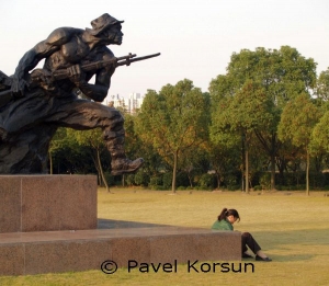 Статуя солдата, пытающаяся наступить на спокойно читающую китаянку