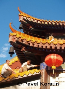 Монахи на крыше буддийского храма, отпугивающие белых голубей