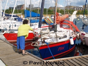 Пожилая женщина с палочкой подтягивает яхту "Питу" к причалу