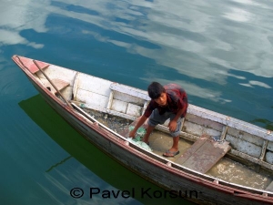 Мальчик-непалец разгружает мешки со щебнем из лодки