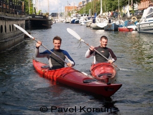 Двое улыбающихся парней катаются на каяках в каналах Копенгагена