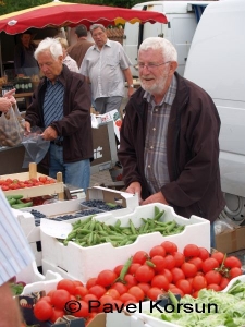 Пожилой мужчина - продавец на продуктовом рынке