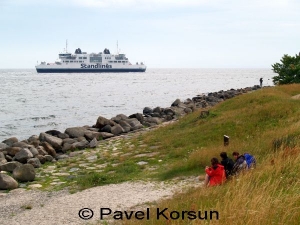 Группа туристов на побережье наблюдает через каменную гряду паром "Scandlines"