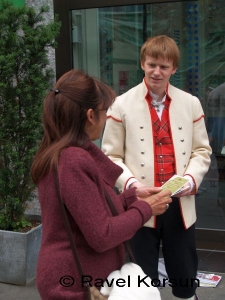 Парень в национальной норвежской одежде общается с женщиной на входе в магазин
