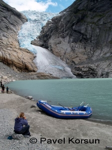 Девушка сидит на камне возле надувной лодки у озера питающегося от Бриксдальского ледника