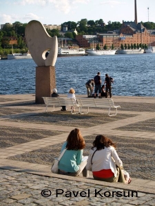 Две девушки, пожилая пара и группа парней возле скульптуры Солнечный ветер