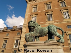 Скульптура льва держащего лапой большой шар на фоне королевского замка в Стокгольме
