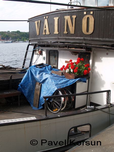 Красные цветы и велосипеды прикрытые тентом на палубе парохода "Ваино"