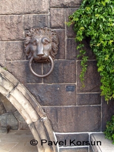 Скульптурный портрет грустного льва держащего большое кольцо в зубах