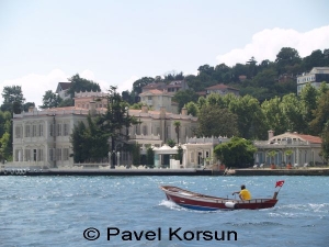 Рыбак на лодке в проливе Босфор на фоне прибрежных дворцов