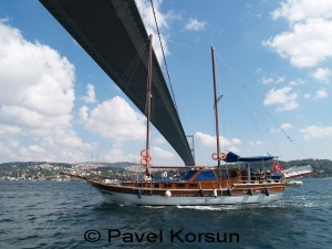 Турецкая яхта Гулет под мостом соединяющим Европу и Азию в проливе Босфор