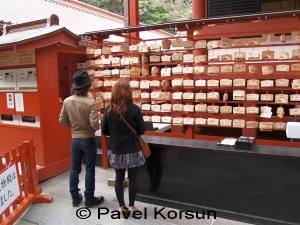 Парень и девушка читают пожелания на деревянных табличках у входа в буддийский храм