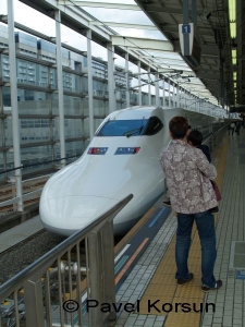 Мужчина с мальчиком смотрят на Шинкансен - скоростной японский поезд 