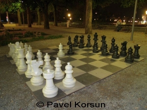 Игра в шахматы в вечернем парке и мужчина сидящий на скамейке